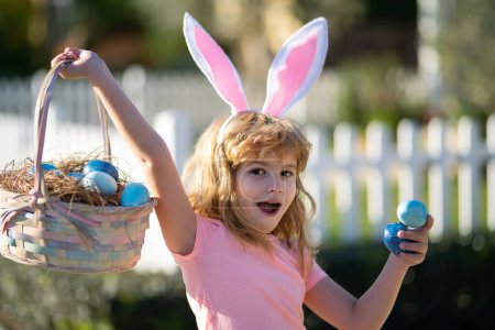 Téléchargez les photos : Enfant chassant des œufs de Pâques. Enfant mignon en costume de lapin avec des oreilles de lapin ayant Pâques. - en image libre de droit