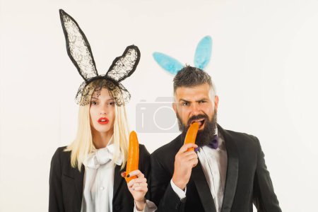 Téléchargez les photos : Lapin de Pâques ou lapin couple avec carotte. Homme drôle femelle. Homme femme grignote une carotte comme un lièvre. Isolé blanc - en image libre de droit
