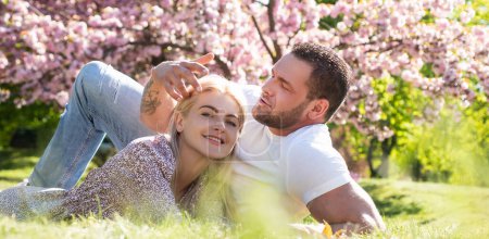 Photo for Couple in love, spring banner. Happy spring couple in love having fun. Two young people relaxing in sakura flowers. Smiling lovers relaxing in park. Family over nature blossom background - Royalty Free Image