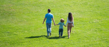 Foto de Family of three, spring banner. Back view of mother father and child son having fun outdoors at summer park - Imagen libre de derechos