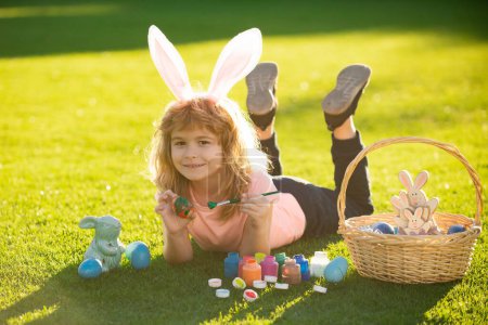 Téléchargez les photos : Child laying on grass in park wit easter eggs. Cute kid having happy easter in park - en image libre de droit