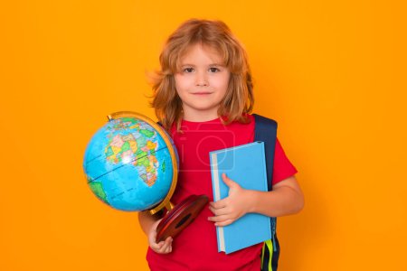 Téléchargez les photos : Isolated portrait of school child. School boy with world globe and book. Kid boy from elementary school. Little student, smart nerd pupil ready to study. Concept of knowledge, education and learning. - en image libre de droit