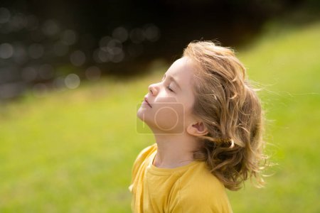 Photo for Child breathing fresh air. Child faith, praise and happiness and freedom. Kid resting in summer park. Kid put face to the sun, closed her eyes and feeds energy of nature, dreams - Royalty Free Image