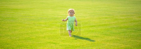 Photo for Baby on spring grass field, banner. Baby play in green grass. Child development. Adorable little kid walking in an autumn field - Royalty Free Image