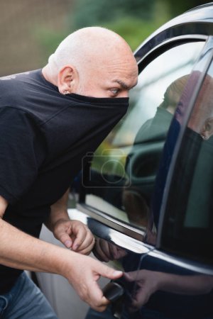 Foto de Thief stealing a car, robber. Car thief steal car breaking door - Imagen libre de derechos