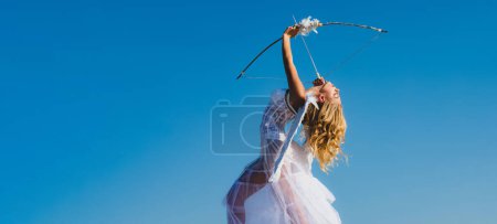 Photo for Valentines day banner with angel teen. Valentines Day. Love and romance. Teenager angel girl with wings aiming with bow and arrow, copy space on sky. Young angel - Royalty Free Image