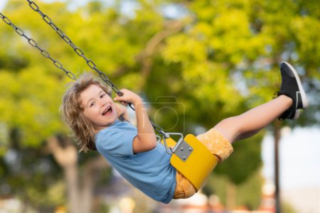 Foto de Outdoor playground. Funny kid on swing. Little boy swinging on playground. Happy cute excited child on swing. Cute child swinging on a swing. Crazy playful child swinging very high - Imagen libre de derechos