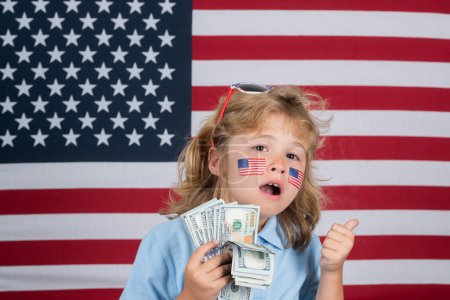 Foto de American dollars money banknotes concept. Kid with money saving. Child with american flag. Memorial day. Funny kids face with american flag on cheek - Imagen libre de derechos