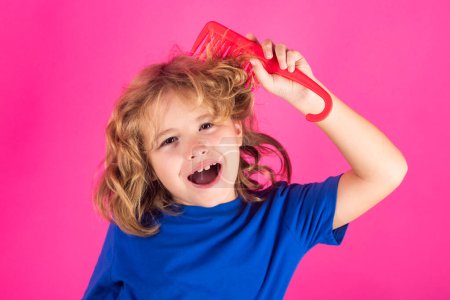 Photo for Funny child with curly blonde hair holding comb hairbrush for combing. Kid hair care. Cute child with comb. Blonde kid combs unruly hair. Kid boy with tangled long hair - Royalty Free Image