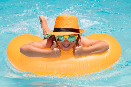 Foto de Cute child in swimming pool with inflatable toy ring. Kids swim on summer pool. Beach sea and water waves background. Summer travelling - Imagen libre de derechos