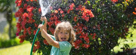 Photo for Spring child watering, banner. Excited little gardener child helping to watering flowers with garden hose in summer garden. Seasonal yard work - Royalty Free Image