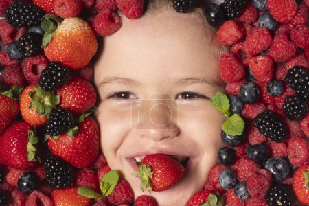 Photo for Fruits for kids. Child face with berry frame, close up. Berries mix blueberry, raspberry, strawberry, blackberry - Royalty Free Image