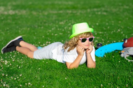 Photo for Child playing in garden. Happy little boy lying on the grass at the spring day. Healthy lifestyle concept - Royalty Free Image