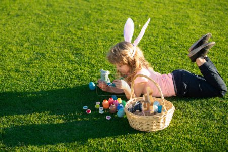 Foto de Feliz conejito de Pascua niño pintando huevos. Primavera niños vacaciones concepto - Imagen libre de derechos