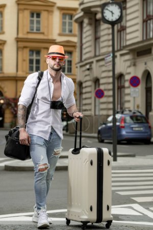 Foto de Man with luggage for vacation, trip. Man tourist with travel bag. Tourist business man traveling in european city. Confident rich business man traveling in european city - Imagen libre de derechos