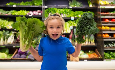 Foto de Kid with vegetables at grocery store. Kid choosing food in grocery store or a supermarket. Fruit and vegetable - Imagen libre de derechos