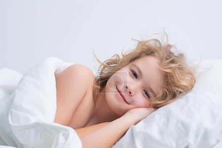 Foto de Quietly sleeping. Child wakes up in the morning in the bedroom. Cute little boy waking up in bed - Imagen libre de derechos