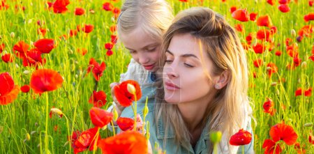 Foto de Mother and daughter on the poppies field background. Spring family banner. Woman with child girl in field with red poppies. Mother and daughter are playing in the field of flowering red poppies - Imagen libre de derechos