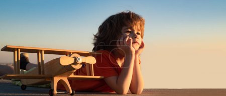 Téléchargez les photos : Child on spring nature background, horizontal photo banner for website header design. Happy kid playing with toy airplane against blue sky background - en image libre de droit