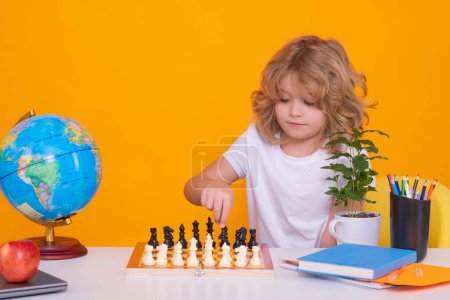 Foto de Portrait of cute child play chess on studio isolated background. Child thinking near chessboard. Learning and growing children, childgood. Kids early development - Imagen libre de derechos