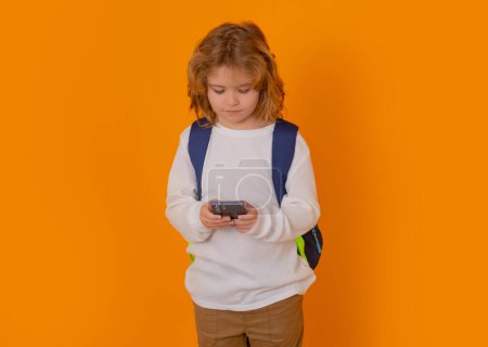 Téléchargez les photos : School kid using phone isolated on yellow isolated studio background - en image libre de droit