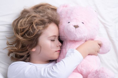 Photo for Daily sleep. Child sleeping with a toy teddy bear on bed. Bedtime, kids sleeps. Kid asleep on pillow, having healthy sleep - Royalty Free Image