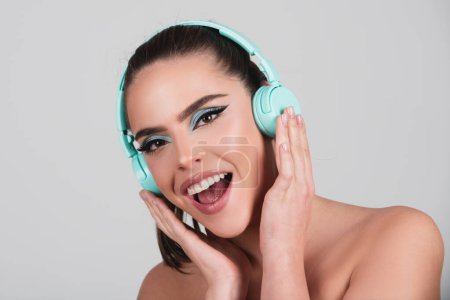 Photo for Excited young woman listen music with headphones, dancing. Girl listening to music using wireless earphones isolated over studio background. Listening radio earphones melody - Royalty Free Image