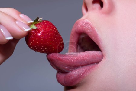 Foto de Strawberry in lips. Red strawberry in woman mouths close up. Lick strawberry - Imagen libre de derechos
