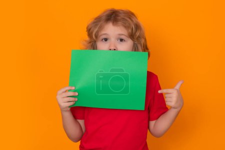 Photo for Kid showing green blank banner on yellow background. Advertising billboard, placard. Child point on empty color blank sheet of paper, copy spase. Poster for your text information - Royalty Free Image