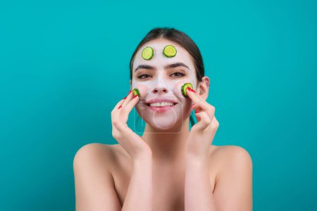 Foto de Woman with facial mask with slices of fresh cucumber on face. Cosmetic procedure. Beauty spa and cosmetology. Spa woman applying facial clay mask. Beauty treatments - Imagen libre de derechos