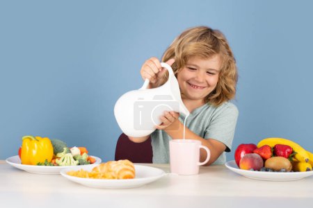 Téléchargez les photos : Kid with dairy milk. Child having a breakfastand pouring milk - en image libre de droit
