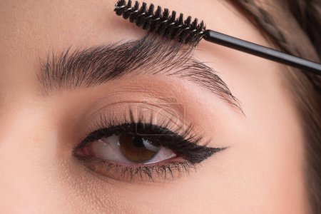 Téléchargez les photos : Closeup eyebrows with eyebrow brush. Close up brows, eyebrows lamination. Brow procedures. Long eyelashes, eyebrows, macro - en image libre de droit