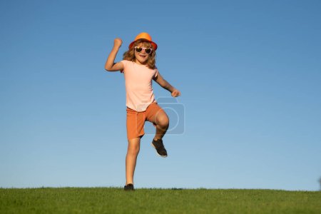 Photo for Kid boy running outdoor. Sport for children. Runner kids race in park. Child having fun and running on green grass near blue sky in park - Royalty Free Image