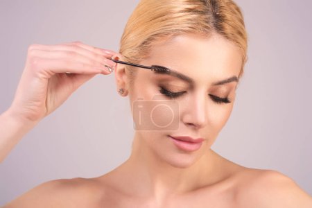 Foto de Woman comb eyebrows with eyebrow brush. Care for brows, eyebrows lamination. Brow beauty procedures. Beautiful woman with long eyelashes, eyebrows - Imagen libre de derechos