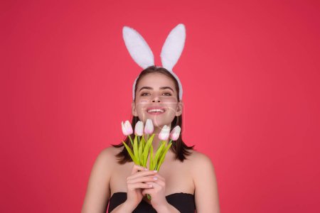 Téléchargez les photos : Portrait de jeune fille se sentant heureuse, célébrant Pâques, porter des oreilles de lapin tenir des œufs peints. Jeune femme en studio portant des oreilles de lapin. Joyeux concept de Pâques. Heureuse femme gaie avec des oreilles de lapin - en image libre de droit