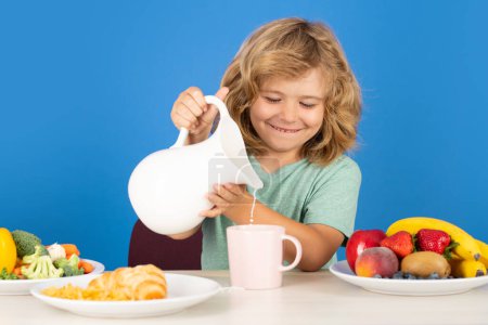 Photo for Child drink dairy milk. Kid having a breakfastand pouring milk - Royalty Free Image