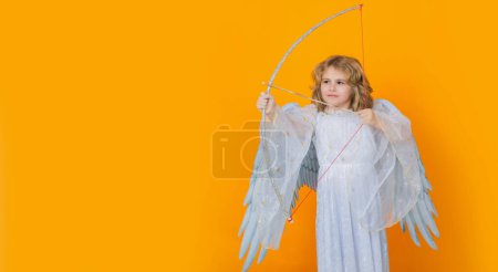 Foto de Ángel con arco y flecha. Un angelito. Retrato de niño lindo con alas de ángel aislado en el fondo del estudio. Banner para el diseño del encabezado del sitio web - Imagen libre de derechos