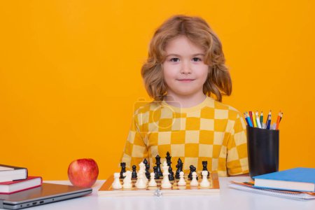 Foto de Child thinking near chessboard. Learning and growing children, childgood. Kids early development. Child with chess on yellow isolated studio background - Imagen libre de derechos