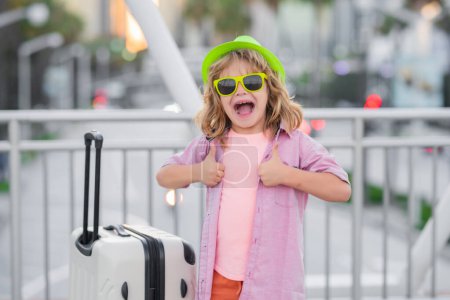 Foto de Excited tourist. Funny child traveller. Child with travel suitcase on vacation. Kids travelling - Imagen libre de derechos