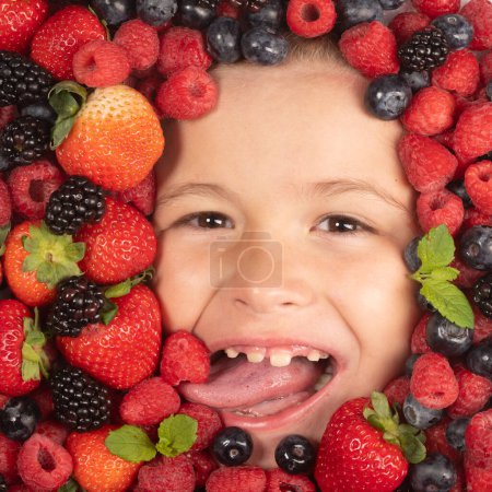 Photo for Fruits for kids. Kids face with close-up berry. Berries mix of strawberry, blueberry, raspberry, blackberry. Assorted mix of strawberry, blueberry, raspberry, blackberry with background near child - Royalty Free Image