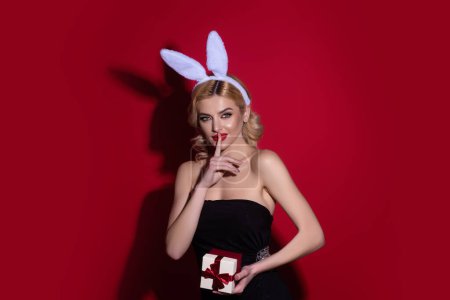 Téléchargez les photos : Easter concept. Portrait of young woman wearing bunny ears holding easter eggs over isolated background in studio. Beautiful girl with rabbit ears hold easter egg, studio shot isolated background - en image libre de droit