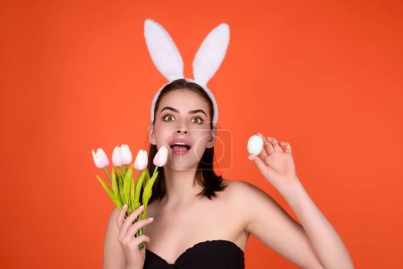 Téléchargez les photos : Photo rapprochée de jolie fille porter des oreilles de lapin pelucheux de Pâques tenir des œufs de Pâques, fond de studio isolé. Portrait mangeur de lapin femelle - en image libre de droit