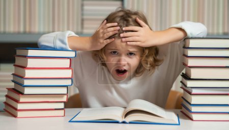 Photo for Expression school kid with piles of books. Knowledge day. School child pupil reading book at school. Kid doing homework, sitting at table by books, in classroom - Royalty Free Image