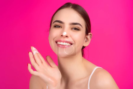 Photo for Skin care. Beauty portrait of a beautiful woman applying face cream isolated on studio background. Young spa model uses body care cream. Facial cream, moisturizing lifting nourishing creme - Royalty Free Image