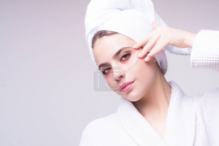 Photo for Skin rejuvenation. Facial care. Beauty treatment. Woman applying under eye patches on healthy fresh face, isolated studio background. Cosmetic mask, patches eyes gel. Hydrogel eye patch - Royalty Free Image