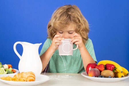 Photo for Kid boy pouring whole cows milk. Portrait of child eat fresh healthy food in kitchen at home. Kid boy eating breakfast before school - Royalty Free Image
