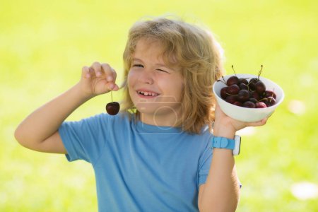 Photo for Cherry and cute child. The child eats cherries. Excited face. Cherry for kids. Teenager child hold plate cherries. Amazed expression, cheerful and glad - Royalty Free Image