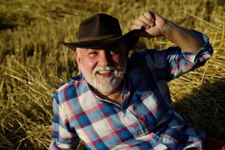 Photo for Happy old farmer in the hay. Senior taking a break and relaxing on a hay on an summer day. Grandfather laying on haystack in countryside. Mature man resting at cereal field - Royalty Free Image