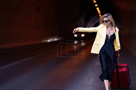 Foto de Sueños de viajar. Mujer de moda con equipaje, maletas de vacaciones. Estilo de vida. Mujer con una maleta tomar un taxi - Imagen libre de derechos