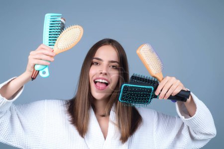 Photo for Beautiful model girl with comb brushing hair. Beauty woman with straight hair on studio background. Woman holding hairbrush near face. Healthy hair. Hairstyle and hair care concept. Shiny hairs - Royalty Free Image